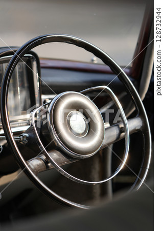 Vintage Classic car steering wheel, with chrome and leather textures in sharp detail, showcases the quality and precision of automotive craftsmanship under natural light. Vintage Classic car steering wheel, with chrome and leather textures in sharp detail, showcases the quality and precision of automotive craftsmanship under natural light. 128732944