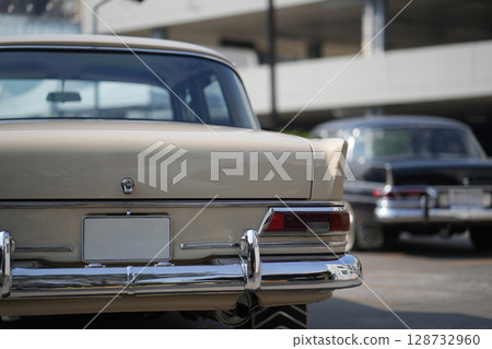 A chrome keyhole above the license plate and a polished rear trunk lock system on a vintage car highlight its sturdy and secure mechanical design. 128732960