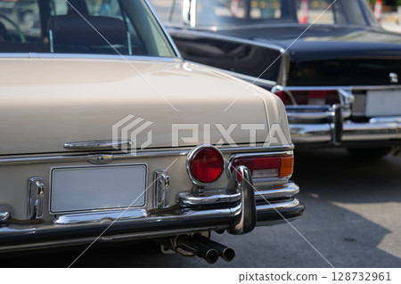 A chrome keyhole above the license plate and a polished rear trunk lock system on a vintage car highlight its sturdy and secure mechanical design. A chrome keyhole above the license plate and a polished rear trunk lock system on a vintage car highlight its sturdy and secure mechanical design. 128732961