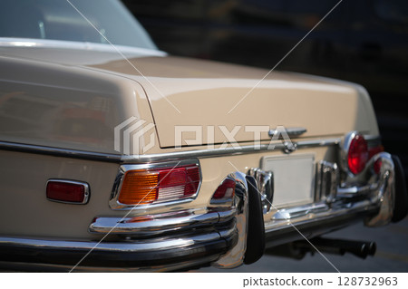 The tail lights, turn signals, and chrome accents on the rear of classic cars exude vintage charm and sophisticated design. 128732963