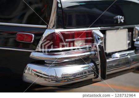 The tail lights, turn signals, and chrome accents on the rear of classic cars exude vintage charm and sophisticated design. 128732964