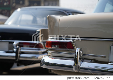 The tail lights, turn signals, and chrome accents on the rear of classic cars exude vintage charm and sophisticated design. 128732966