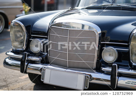 The round headlights and side turn signals on classic cars, framed in polished chrome, highlight the vintage style with old-fashioned lighting and curved fender details. The round headlights and side turn signals on classic cars, framed in polished chrome, highlight the vintage style with old-fashioned lighting and curved fender details. 128732969
