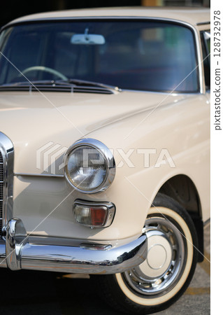 The round headlights and side turn signals on classic cars, framed in polished chrome, highlight the vintage style with old-fashioned lighting and curved fender details. The round headlights and side turn signals on classic cars, framed in polished chrome, highlight the vintage style with old-fashioned lighting and curved fender details. 128732978