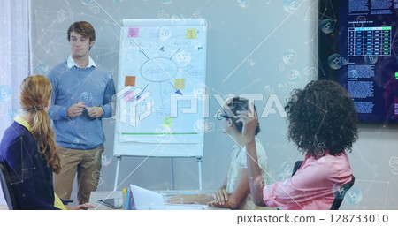 Talking man in blue sweater explaining mind-map on flip chart in meeting room, with sticky notes Talking man in blue sweater explaining mind-map on flip chart in meeting room, with sticky notes 128733010