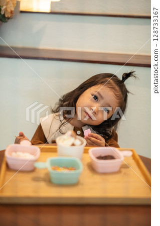 toddler girl eating ice cream dessert with spoon 128733167