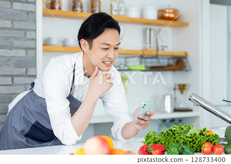 Kitchen: Man looking at smartphone 128733400