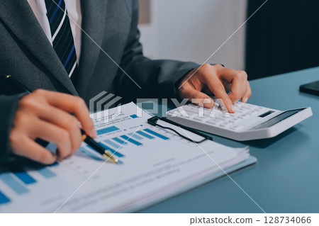 Business financing accounting banking concept. Business woman hand doing finances and calculate on desk about cost at home office. Woman working on desk with using calculator, finance accounting. Business financing accounting banking concept. Business woman hand doing finances and calculate on desk about cost at home office. Woman working on desk with using calculator, finance accounting. 128734066