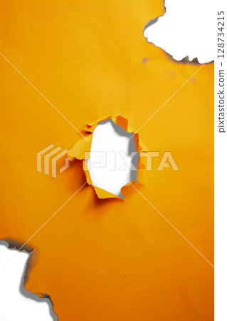 Burnt and torn hole in the orange paper reveals a white background. Copy space Burnt and torn hole in the orange paper reveals a white background. Copy space 128734215