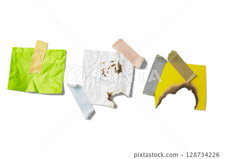 Burnt white and yellow paper with green crumpled paper on adhesive masking tape isolated over a white background. Copy space 128734226
