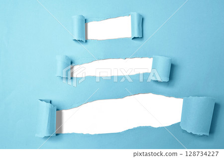 Set of torn blue paper revealing a white background. Copy space 128734227