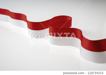 The striped red and white ribbon of the Indonesian flag on a white background. Concept of Indonesian Independence Day or Kemerdekaan The striped red and white ribbon of the Indonesian flag on a white background. Concept of Indonesian Independence Day or Kemerdekaan 128734252