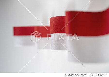 The striped red and white ribbon of the Indonesian flag on a white background. Concept of Indonesian Independence Day or Kemerdekaan The striped red and white ribbon of the Indonesian flag on a white background. Concept of Indonesian Independence Day or Kemerdekaan 128734258