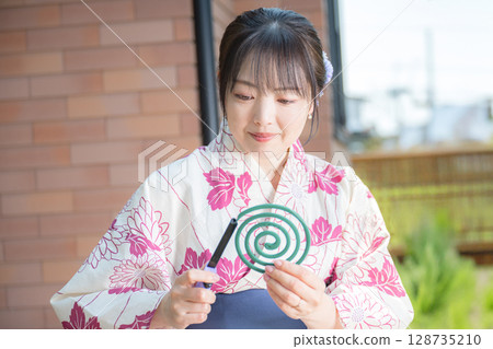 一位身穿浴衣的女士點燃了蚊香 一位身穿浴衣的女士點燃了蚊香 128735210