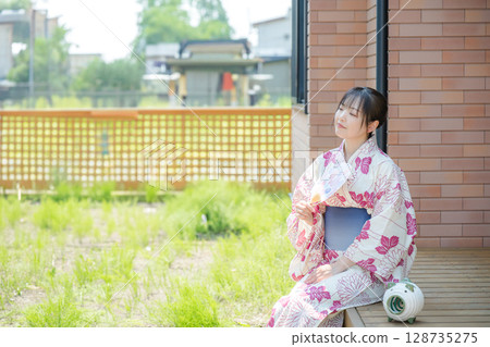 A woman in a yukata cooling off in the garden 128735275