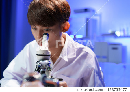 Young scientist looking through a microscope in the laboratory. Young scientist looking through a microscope in the laboratory. 128735477