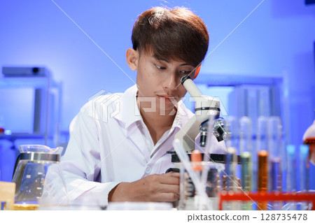Young scientist looking through a microscope in the laboratory. Young scientist looking through a microscope in the laboratory. 128735478