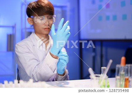 Scientist preparing for experiment with protective glove Scientist preparing for experiment with protective glove 128735498