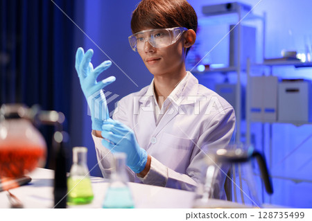 Scientist preparing for experiment with protective glove Scientist preparing for experiment with protective glove 128735499