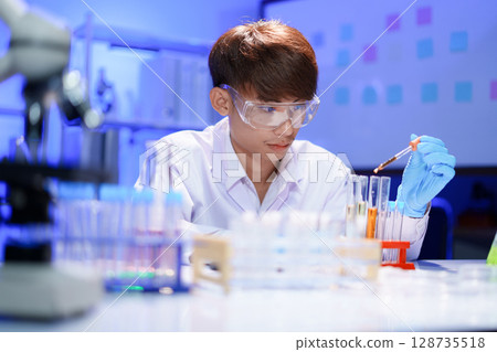 Scientists working in Laboratory using pipette dropping liquid sample into test tube. Scientists working in Laboratory using pipette dropping liquid sample into test tube. 128735518