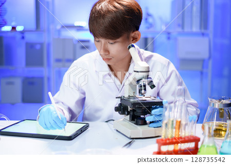 Scientist recording the results of the study in a laboratory journal. Scientist recording the results of the study in a laboratory journal. 128735542