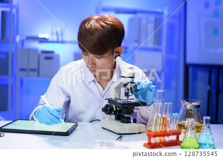 Scientist recording the results of the study in a laboratory journal. Scientist recording the results of the study in a laboratory journal. 128735545