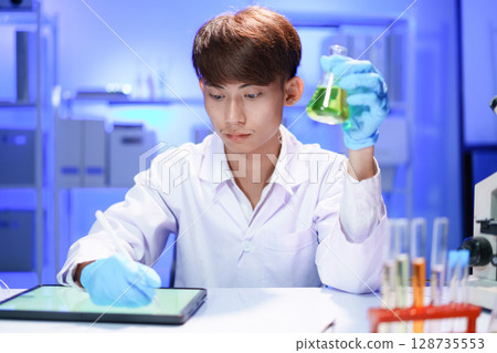 Scientist recording the results of the study in a laboratory journal. 128735553