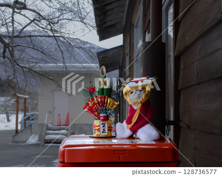 A cute decoration of a mini New Year's pine decoration and a cat in a costume on top of a mailbox 128736577