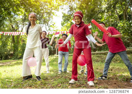 Portrait of an Indonesian southeast asian people celebrate Indonesia Independence Day on the 17th of August with a game of keep the balloon from blowing out outdoors. Concept of Kemerdekaan Indonesia Portrait of an Indonesian southeast asian people celebrate Indonesia Independence Day on the 17th of August with a game of keep the balloon from blowing out outdoors. Concept of Kemerdekaan Indonesia 128736874