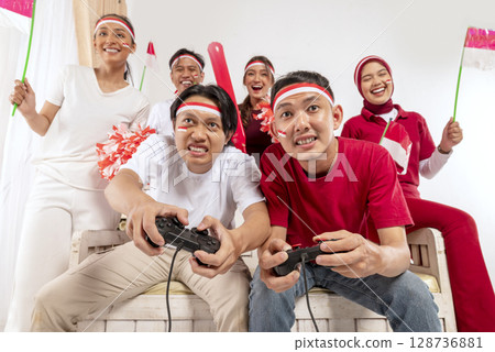 Portrait of an Indonesian southeast asian people celebrate Indonesia Independence Day on the 17th of August with a game of playing video games at home. Concept of Kemerdekaan Indonesia Portrait of an Indonesian southeast asian people celebrate Indonesia Independence Day on the 17th of August with a game of playing video games at home. Concept of Kemerdekaan Indonesia 128736881