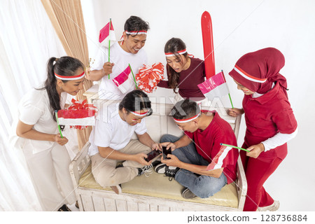 Portrait of an Indonesian southeast asian people celebrating Indonesia Independence Day on the 17th of August with a game of playing video games on cellphone at home. Concept of Kemerdekaan Indonesia Portrait of an Indonesian southeast asian people celebrating Indonesia Independence Day on the 17th of August with a game of playing video games on cellphone at home. Concept of Kemerdekaan Indonesia 128736884
