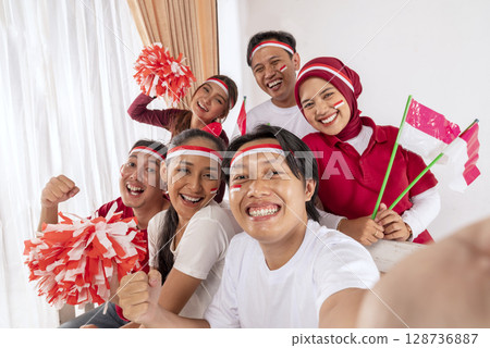 Portrait of an Indonesian southeast asian people celebrating Indonesia Independence Day on the 17th of August by taking a selfie with a cellphone at home. Concept of Kemerdekaan Indonesia Portrait of an Indonesian southeast asian people celebrating Indonesia Independence Day on the 17th of August by taking a selfie with a cellphone at home. Concept of Kemerdekaan Indonesia 128736887