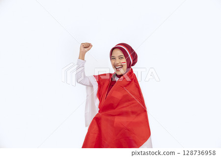 Indonesian southeast asian woman celebrating Indonesia Independence Day on the 17th of August by holding the Indonesian national flag isolated over a white background. Concept of Kemerdekaan Indonesia 128736958