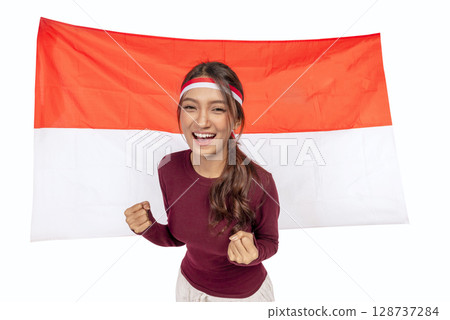 Indonesian southeast asian woman celebrating Indonesia Independence Day on the 17th of August with the Indonesian national flag isolated over a white background. Concept of Kemerdekaan Indonesia 128737284