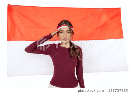 Indonesian southeast asian woman celebrating Indonesia Independence Day on the 17th of August with the Indonesian national flag isolated over a white background. Concept of Kemerdekaan Indonesia 128737285