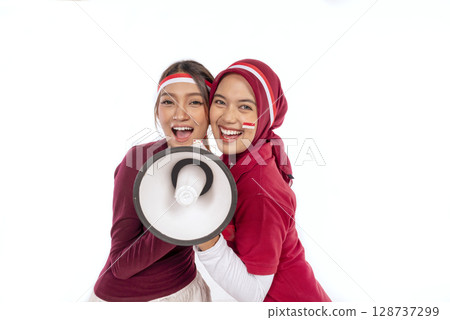 Indonesian southeast asian women celebrate Indonesia Independence Day 17th August with Indonesian national flag ornament holding megaphone isolated white background. Concept of Kemerdekaan Indonesia 128737299