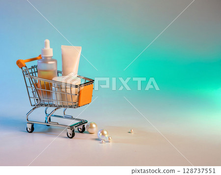 Skincare products in mini shopping cart with pearls on turquoise gradient background for beauty and cosmetic concept 128737551