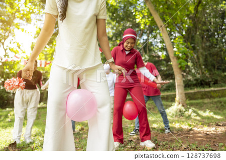Portrait of an Indonesian southeast asian people celebrate Indonesia Independence Day on the 17th of August with a game of keep the balloon from blowing out outdoors. Concept of Kemerdekaan Indonesia Portrait of an Indonesian southeast asian people celebrate Indonesia Independence Day on the 17th of August with a game of keep the balloon from blowing out outdoors. Concept of Kemerdekaan Indonesia 128737698