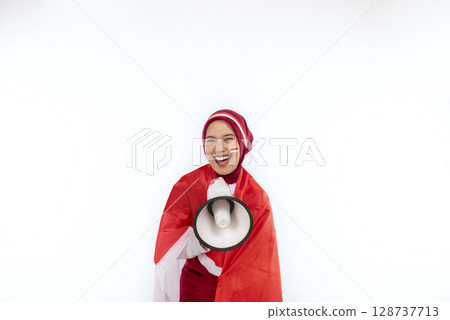 Indonesian southeast asian woman celebrating Indonesia Independence Day on 17th August by holding the Indonesian national flag and megaphone isolated white background. Concept of Kemerdekaan Indonesia 128737713