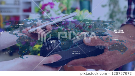 Customer and clerk exchanging payment at plant shop with smartphone, card reader, world map overlay 128737972