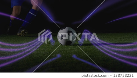 Running athlete in blue kit approaching soccer ball on field at night, gold cleats, purple streaks 128738221