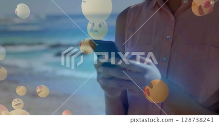 Image of falling emoji over african american woman using smartphone 128738241