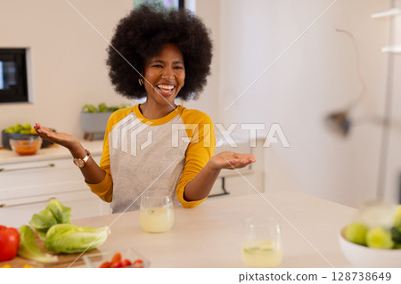 African American woman welcoming viewers at kitchen island, showing lettuce, tomatoes and lemonade African American woman welcoming viewers at kitchen island, showing lettuce, tomatoes and lemonade 128738649