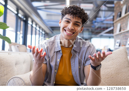 Young adult man sitting on beige sofa with potted plant and wristwatch in modern office lounge Young adult man sitting on beige sofa with potted plant and wristwatch in modern office lounge 128738650