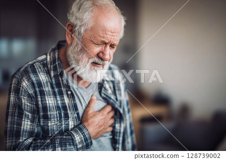 An elderly man holds his chest with his hand, expressing intense pain or discomfort, and his face and eyes show suffering and anxiety. 128739002