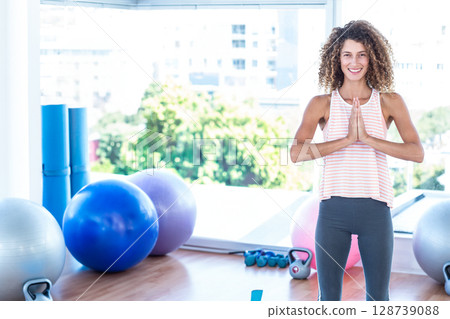Woman practicing yoga pose in studio, with stability balls and foam rollers, copy space 128739088