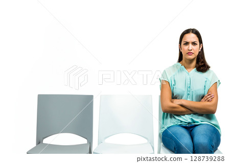 Woman sitting on plastic chairs in empty studio, crossing arms, legs with stern look, copy space 128739288