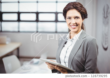 Businesswoman smiling and holding tablet in conference room near table with coffee cup, copy space 128739295