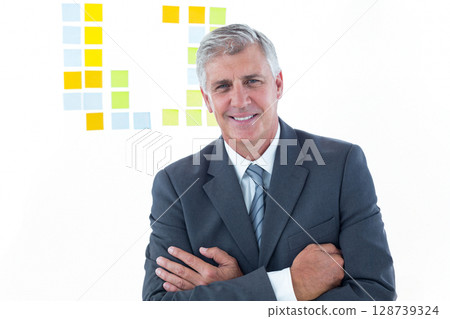 Senior man standing with arms crossed in modern meeting room, with pastel sticky notes, copy space 128739324