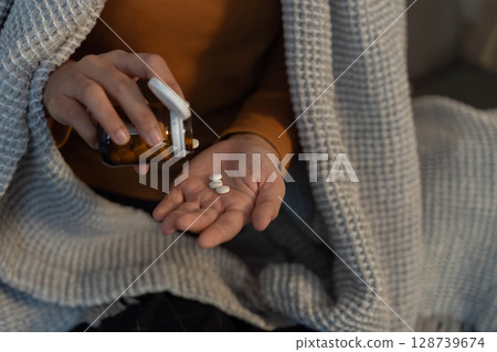 Medication Management. Individual taking pills from a bottle. 128739674